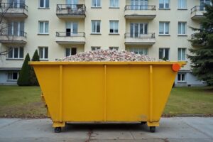 Gelbe Absetzmulde mit sortenreinem Bauschutt vor einem Wohnhaus